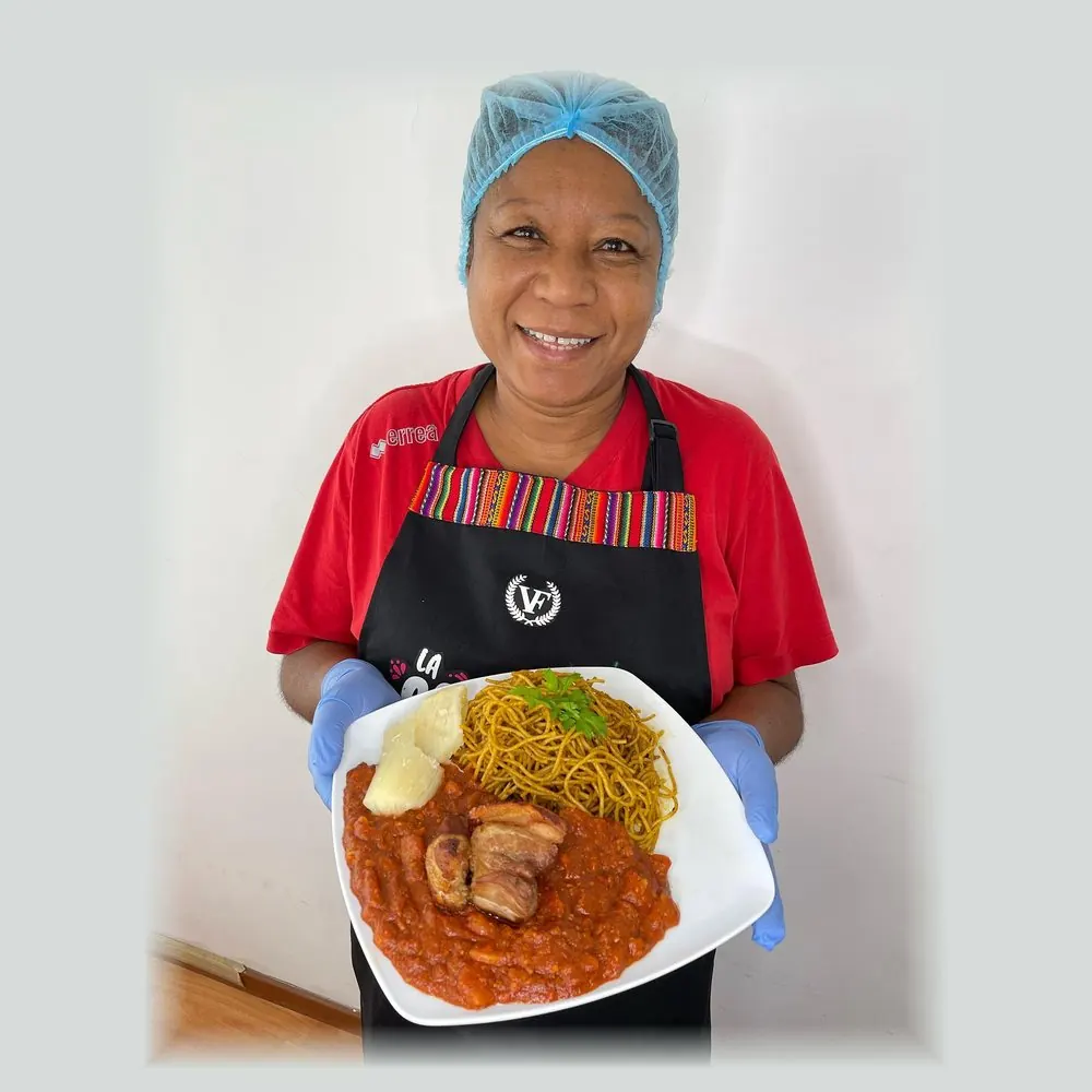 La Cotito sonriendo con un plato de carapulcra con sopa seca